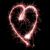 a glowing red sparkling love heart shape on a black background