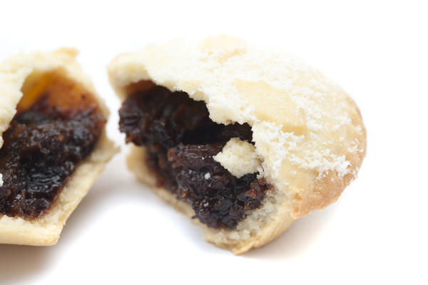 Partially eaten mince pie showing the spicy rich fruity filling and freshly baked golden crust, close up view