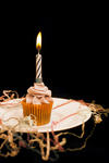 Burning candle on an orange cupcake with decorative icing to celebrate Halloween or a childs birthday