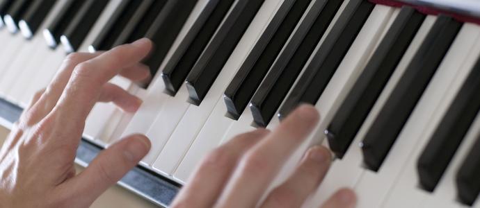 stock image hands palying a full sized piano keyboard