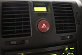 Background of a car dashboard with focus to the central red hazard warning light