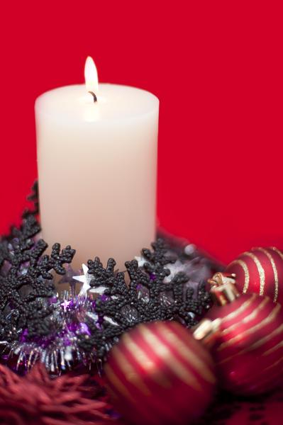christmas candle, baubles, decorations and tinsel garland on a red background