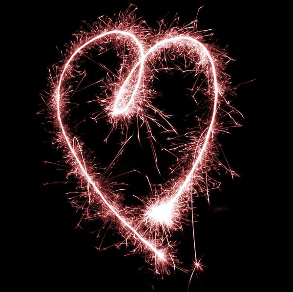 a glowing red sparkling love heart shape on a black background