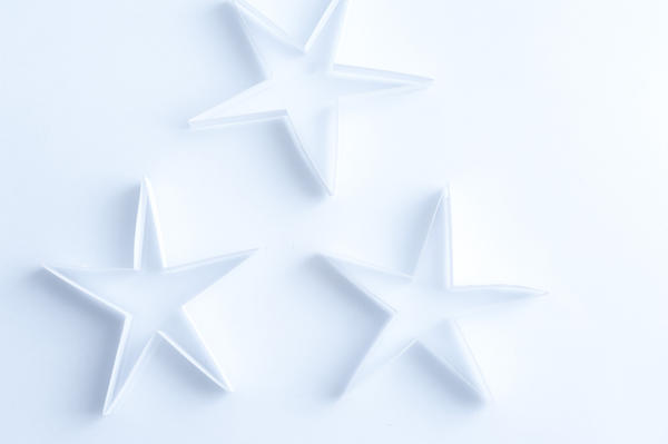 Delicate fragile paper stars on a white background for an ethereal spiritual Christmas background