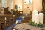 a view of the inside of a church, decorated with white flowers and white church candles