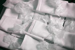 a pile of white linen napkins decorated with white lace ribbon for a wedding breakfast