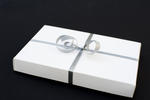 a white gift box bound with a silver coloured ribbon