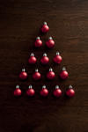Christmas baubles tree shape with colorful red balls arranged in a triangle to resemble a modern Xmas tree over a dark background